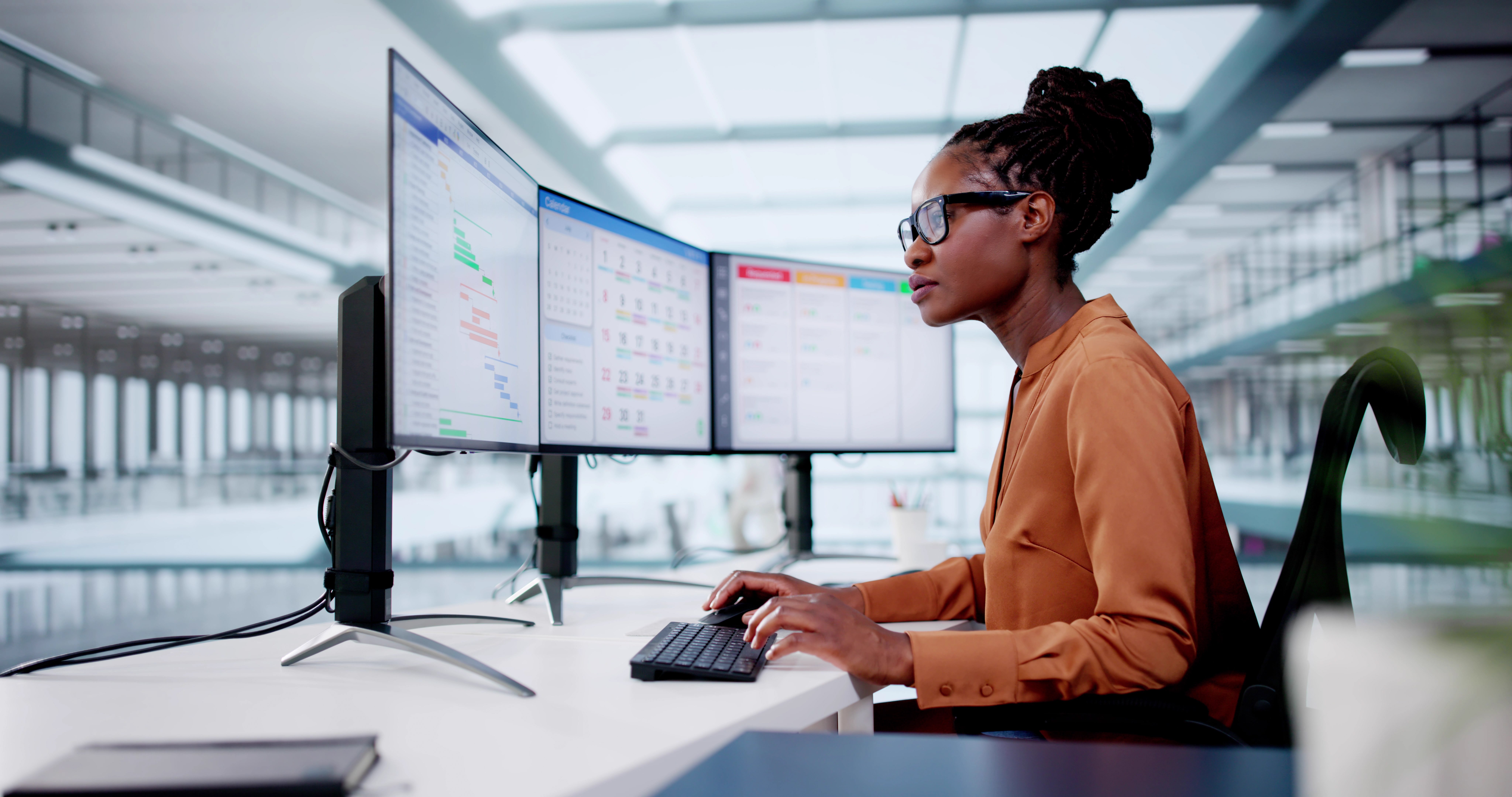 Image of woman on computer with three monitors